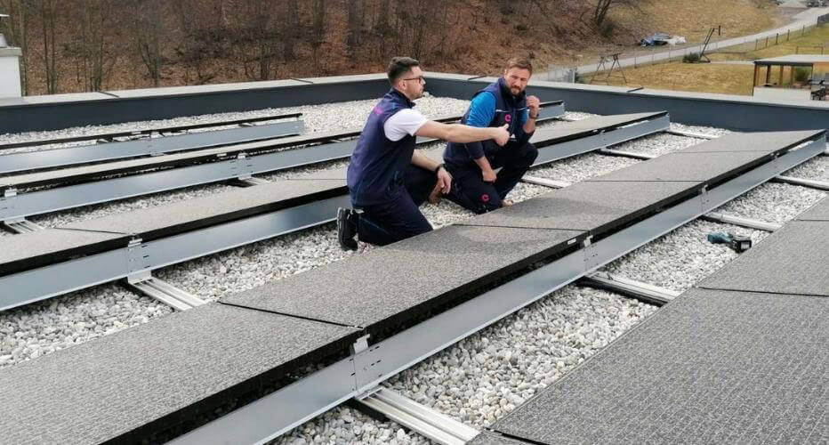 Strokovnjaka opravljata pregled soncne elektrarne na strehi. 